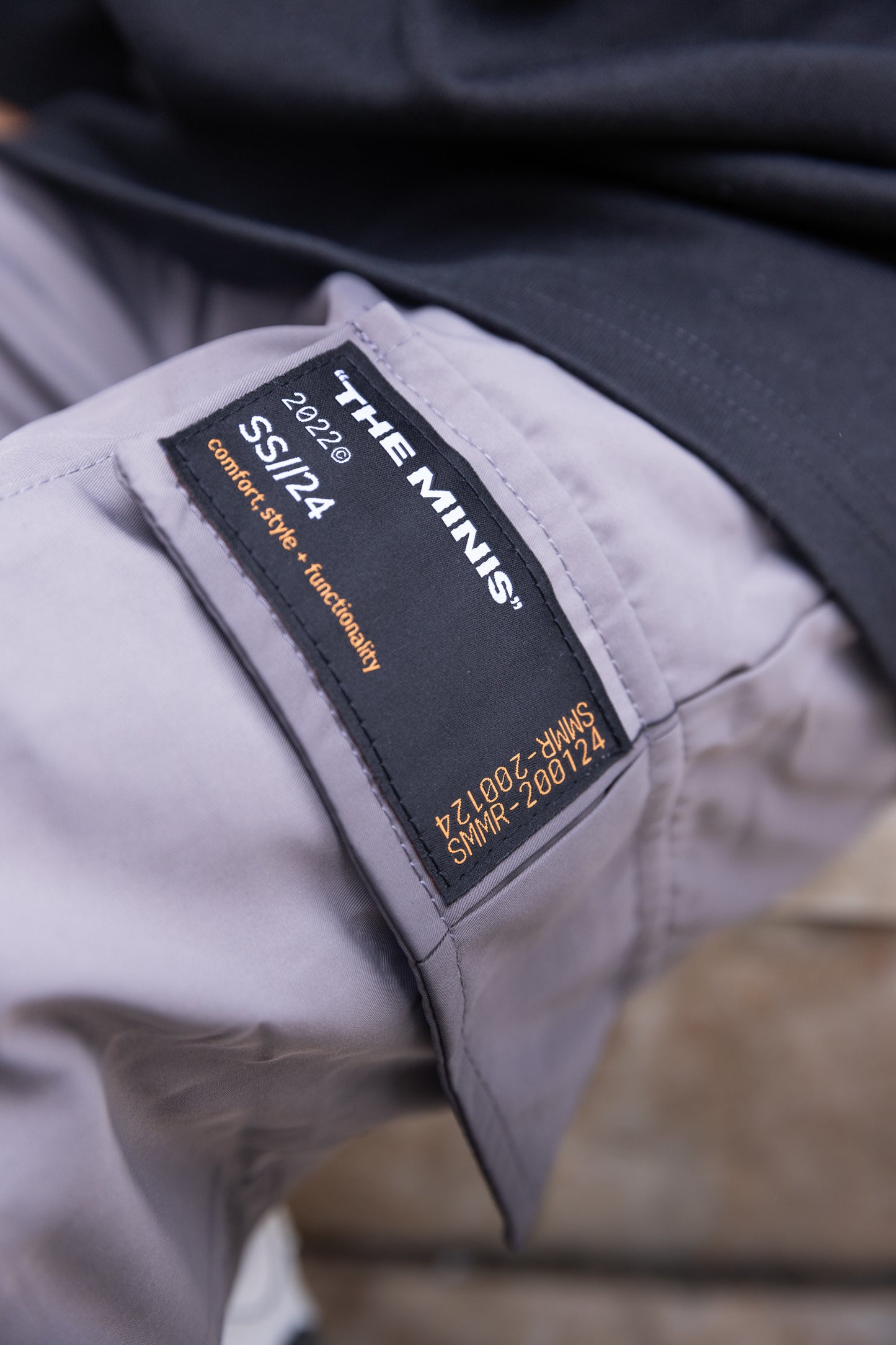 Light grey pants with black 'THE MINIS' SS//24 label, featuring 'comfort, style + functionality' & code SMMR-200124.