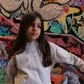 Child in white hoodie and pants with 'THE MINIS.' text, standing against a vibrant graffiti backdrop.