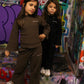 Kids wearing 'the minis.' ribbed brown and black long-sleeve outfits, street art background.