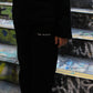 Black pants with 'the minis.' text, black long-sleeve top, and sneakers worn by a person on graffiti steps.